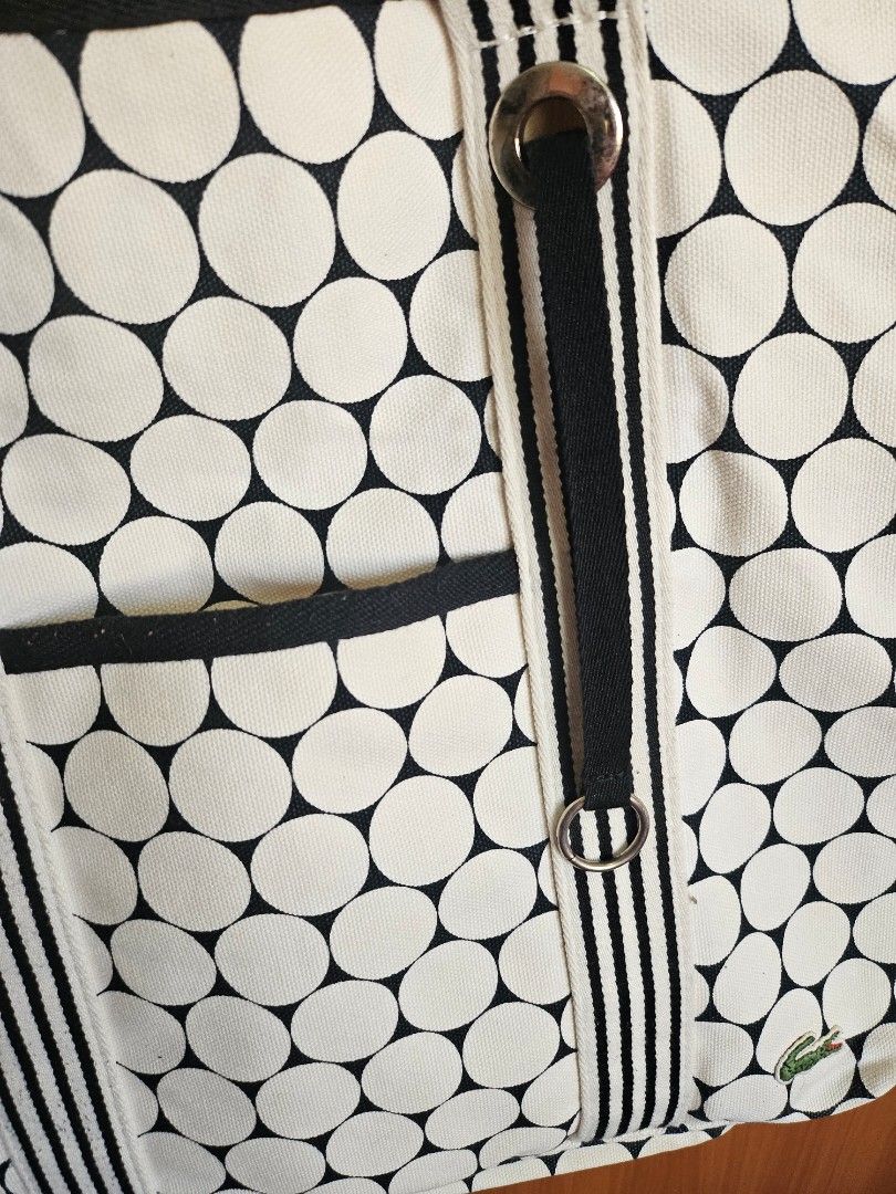 Lacoste Golf Ball Design Beach Bag (Category: Tote Bags) located in Mandaluyong City. Submitted by ohwmaria (Listing ID 1470232205, Image 3). Description: - Authentic Lacoste canvas tote bag in a chic black and white polka dot print - Sturdy striped webbing handles accented with silver-tone grommets and rings - Convenient exterior slip pocket on the front for quick-access items - Classic embroidered green crocodile logo patch near the top corner 