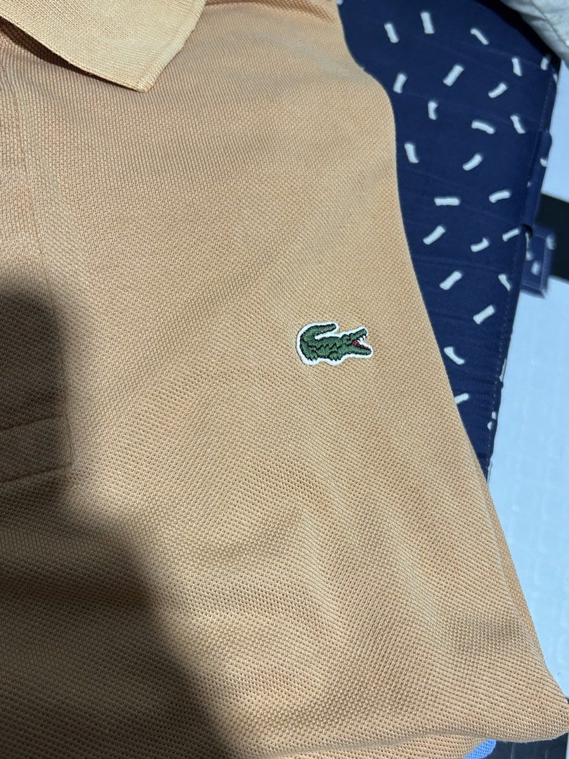 Lacoste Orange Polo Shirt Size 8 (Category: Tshirts & Polo Shirts ) located in San Simon. Submitted by ericdeinla69664 (Listing ID 1470189098, Image 3). Description: - Brand: Lacoste - Color: Vibrant Orange - Size: 8 - Material: 100% Cotton - Design: Classic two-button collar with embroidered green crocodile logo - Origin: Designed in France, Made in El Salvador - Style: Solid color casual wear - Authenticity tags attached (RN 87651, CA 16998).