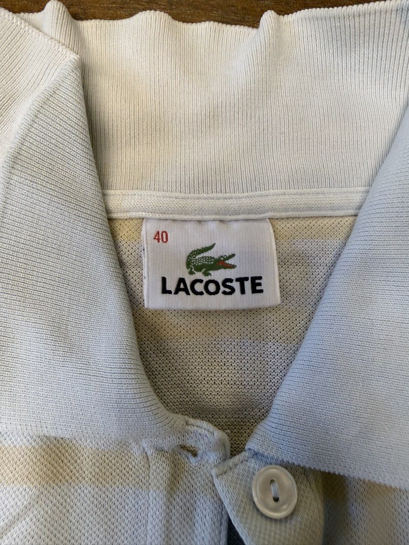 Lacoste Striped Polo Shirt Size 40 (Category: Shirts) located in Muntinlupa City. Submitted by el1b12345 (Listing ID 1470182863, Image 3). Description: - Brand: Lacoste - Style: Striped polo shirt (Light blue and beige) - Size: 40 - L - 22" - W - 17" - Material: Breathable cotton knit fabric - Details: Classic ribbed collar, two-button placket, iconic embroidered green crocodile logo - Condition: Excellent / Great for casual everyday wear - Shipp