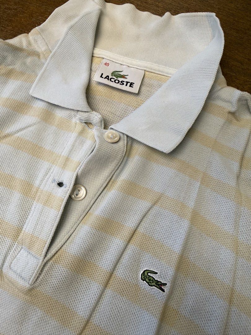 Lacoste Striped Polo Shirt Size 40 (Category: Shirts) located in Muntinlupa City. Submitted by el1b12345 (Listing ID 1470182863, Image 2). Description: - Brand: Lacoste - Style: Striped polo shirt (Light blue and beige) - Size: 40 - L - 22" - W - 17" - Material: Breathable cotton knit fabric - Details: Classic ribbed collar, two-button placket, iconic embroidered green crocodile logo - Condition: Excellent / Great for casual everyday wear - Shipp