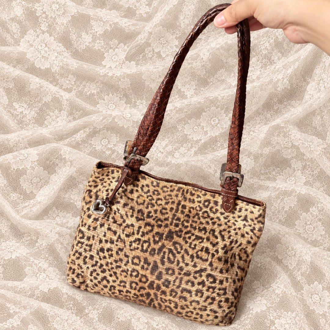 Leopard print shoulder bag with braided brown leather straps (Category: Shoulder Bags) located in Manila. Submitted by calliope777 (Listing ID 1470214919, Image 1). Description: - Eye-catching leopard print fabric shoulder bag - Brown braided leather handles secured with stylish metal buckles - Adorable small heart charm hanging near the strap base - Structured rectangular base helps the bag keep its shape - Divided main interior compartment for 