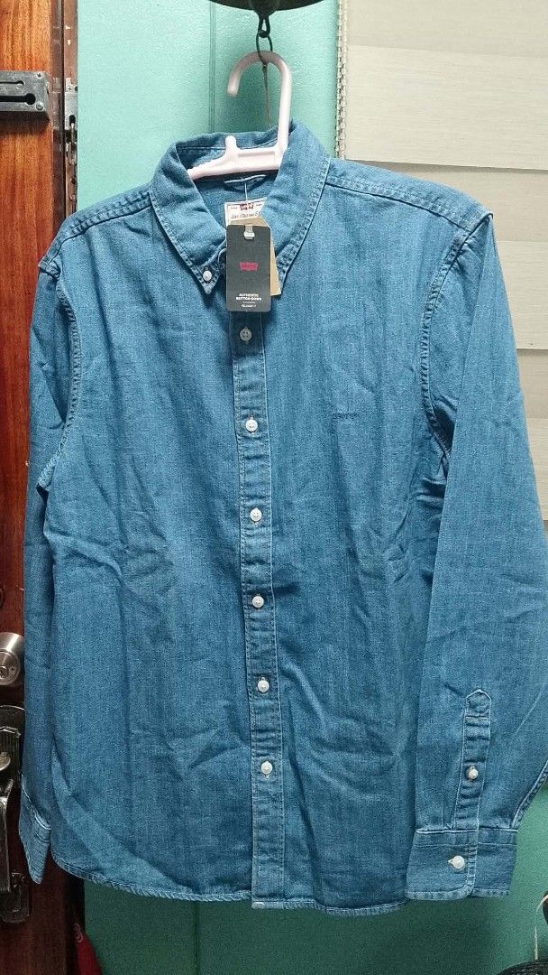 Levi's Authentic Button-Down Relaxed Fit Denim Shirt (Category: Tshirts & Polo Shirts ) located in Cavite. Submitted by elangtayag (Listing ID 1470263415, Image 1). Description: - Brand: Levi's - Item: Authentic button-down denim shirt - Color: Classic Blue - Fit: Relaxed fit with long sleeves - Details: White buttons, embroidered Levi's chest logo - Condition: Brand new with original retail tags attached - Styling: Versatile piece, perfect worn 