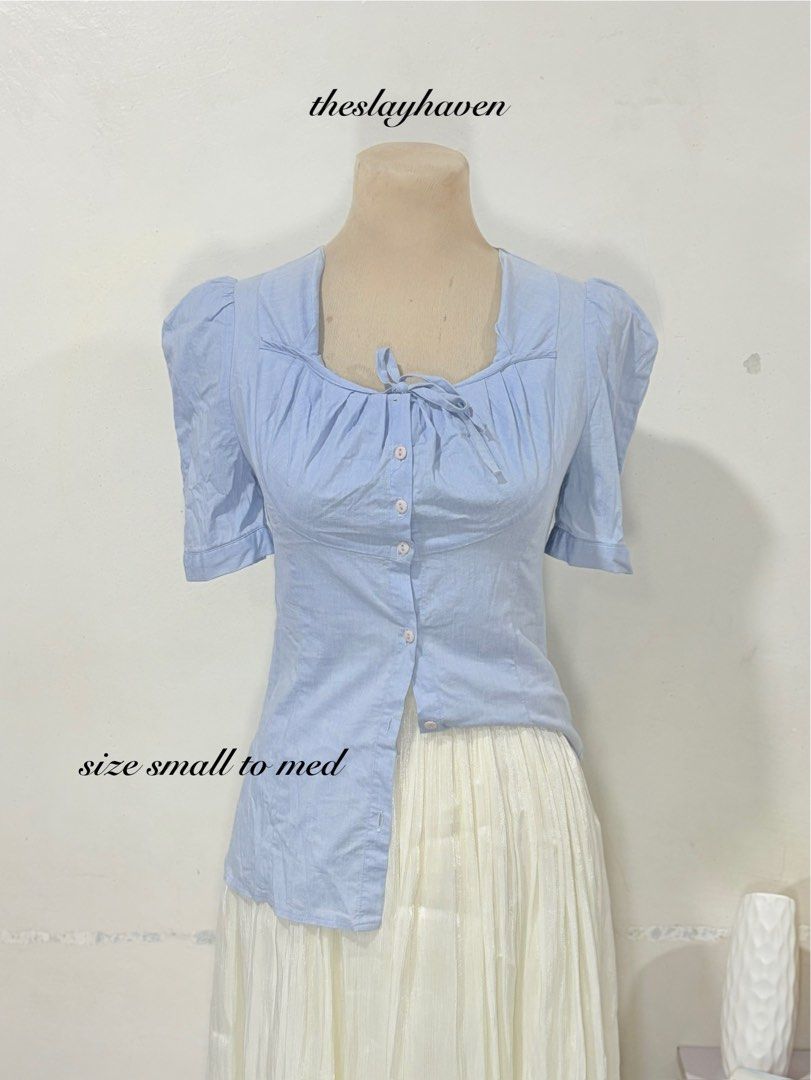 Light Blue Puff Sleeve Blouse Size Small to Medium (Category: Blouses) located in Manila. Submitted by biacakes (Listing ID 1470261239, Image 1). Description: - Color: Light blue - Style: Short-sleeve blouse with trendy puff sleeves - Neckline: Square neck with center front tie detail - Closure: Functional front button placket with matching round buttons - Fit: S to M, features pleated gathering around the bust - Pairing: Great for everyday styli