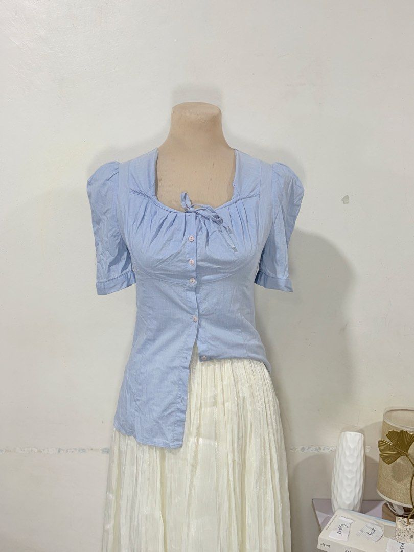 Light Blue Puff Sleeve Blouse Size Small to Medium (Category: Blouses) located in Manila. Submitted by biacakes (Listing ID 1470261239, Image 2). Description: - Color: Light blue - Style: Short-sleeve blouse with trendy puff sleeves - Neckline: Square neck with center front tie detail - Closure: Functional front button placket with matching round buttons - Fit: S to M, features pleated gathering around the bust - Pairing: Great for everyday styli
