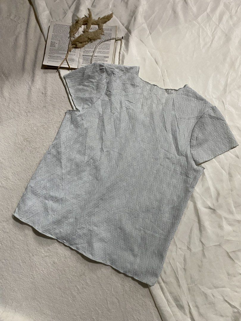 Light blue textured short sleeve v-neck top Small-Medium 36 (Category: Blouses) located in Poro. Submitted by joyceyuu (Listing ID 1470184367, Image 3). Description: - Color: Light blue - Neckline: V-neck - Details: Subtle diamond pattern texture, cap sleeves with gentle pleats - Fit: Casual, lightweight, and easy to pair with jeans or skirts - Condition: Clean and ready to wear.