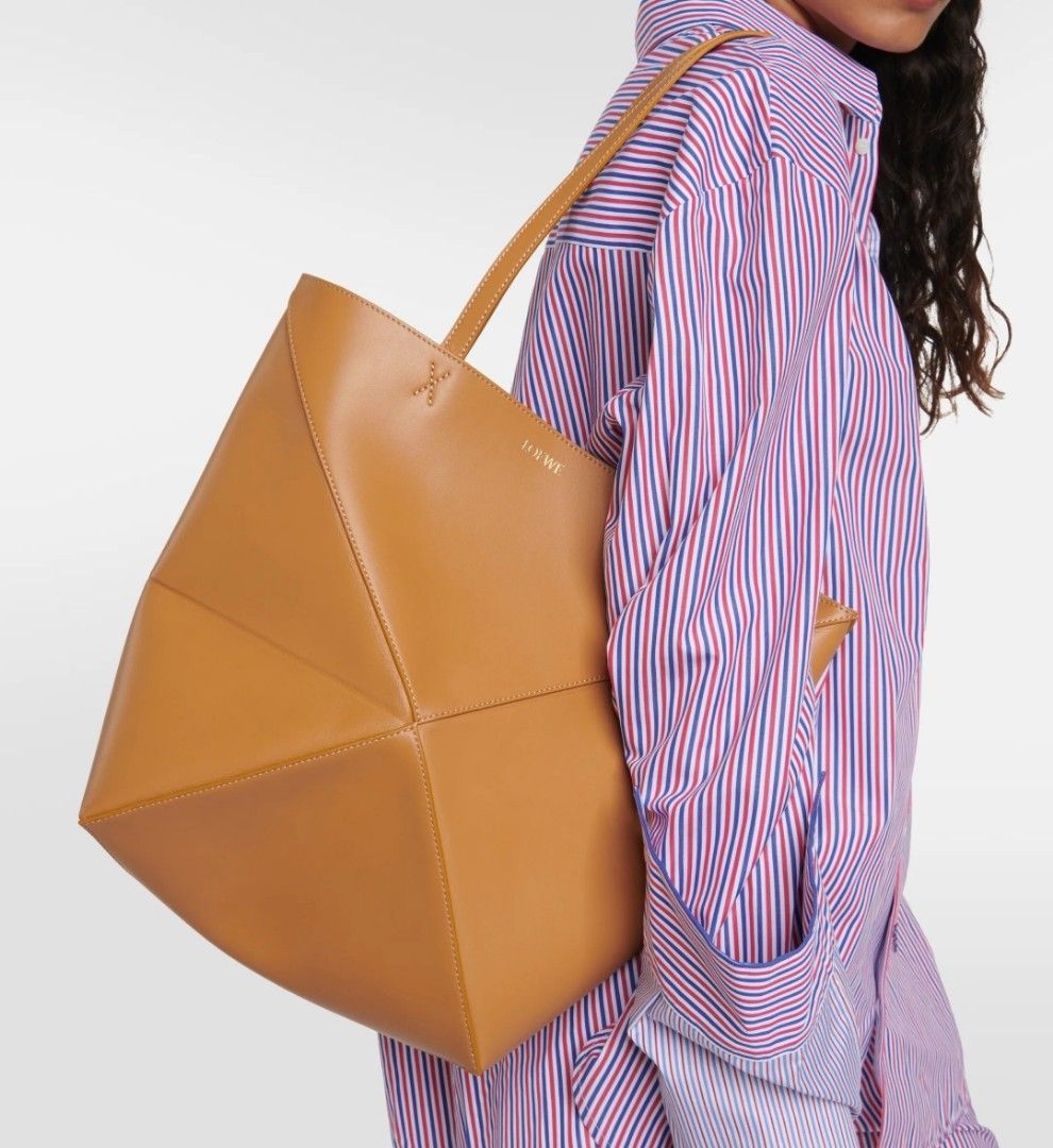 Loewe Puzzle Fold Tote Tan Leather (Category: Tote Bags) located in Caloocan City. Submitted by mylove326 (Listing ID 1470267693, Image 2). Description: - Brand: Loewe - Material: Smooth calfskin leather in a versatile tan shade - Design: Structured geometric panel with unique folded construction - Details: Subtle gold embossed logo and contrast stitching near strap bases - Straps: Dual shoulder straps for comfortable daily wear - Closure: Open t
