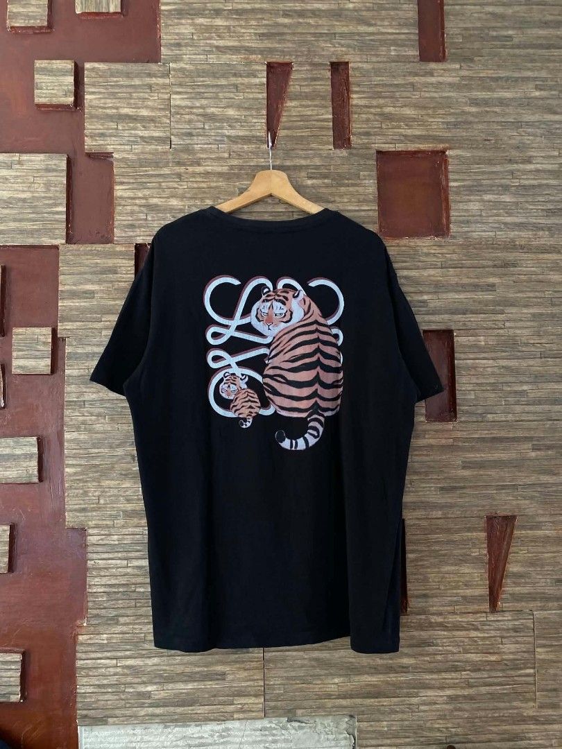 Loewe Tiger Print Black T-Shirt (Category: Shirts) located in Alegria. Submitted by happypenguin-d20d (Listing ID 1470214942, Image 2). Description: Black t-shirt from Loewe. Small tiger graphic and brand lettering printed on the chest. Large tiger graphic with intertwined logo design printed on the back. Short sleeves, classic crew neck. Cotton fabric, standard relaxed fit..