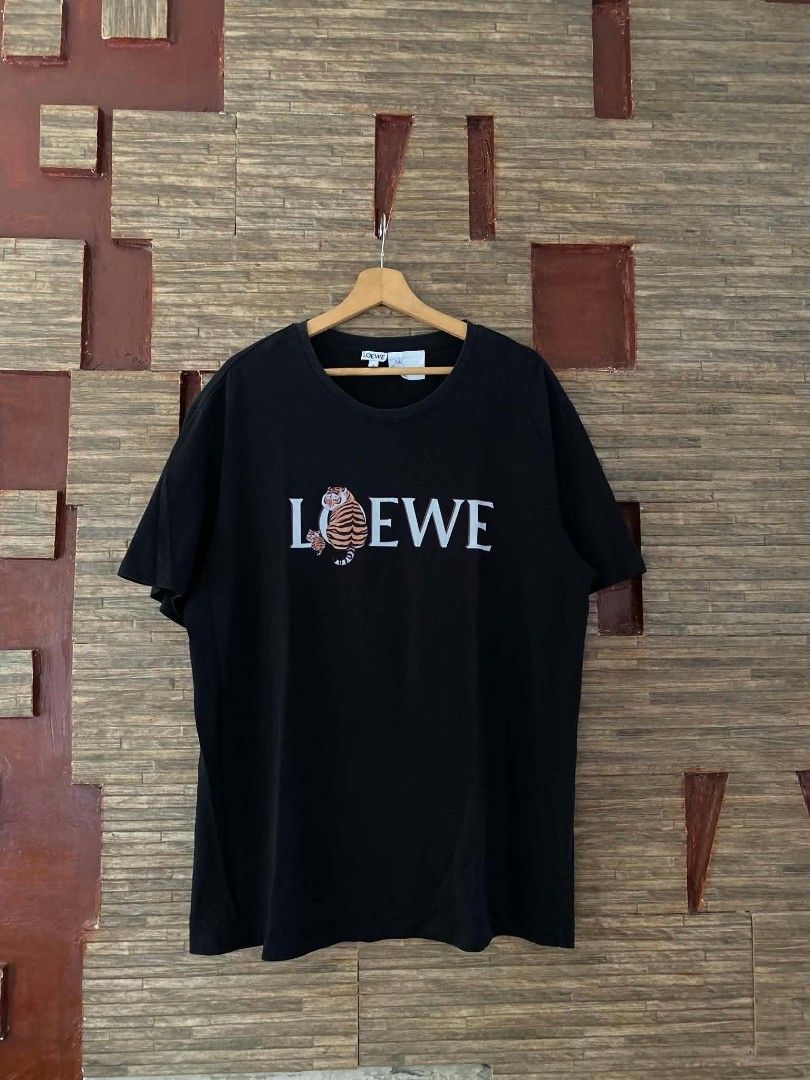 Loewe Tiger Print Black T-Shirt (Category: Shirts) located in Alegria. Submitted by happypenguin-d20d (Listing ID 1470214942, Image 1). Description: Black t-shirt from Loewe. Small tiger graphic and brand lettering printed on the chest. Large tiger graphic with intertwined logo design printed on the back. Short sleeves, classic crew neck. Cotton fabric, standard relaxed fit..