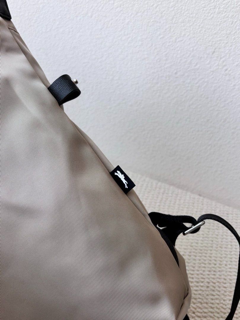 Longchamp Backpack (Category: Backpacks) located in Singapore. Submitted by sg_vela_professional_seller (Listing ID 1470204313, Image 6). Description: - Brand: Longchamp - Color: Neutral beige with black accents and hardware - Material: Lightweight, durable nylon fabric with sturdy straps - Features: Signature Longchamp branding, secure zippered outer pocket, and adjustable shoulder straps - Condition: Brand new and unused - Ideal for: Everyday c