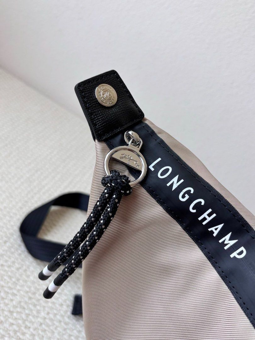 Longchamp Backpack (Category: Backpacks) located in Singapore. Submitted by sg_vela_professional_seller (Listing ID 1470204313, Image 3). Description: - Brand: Longchamp - Color: Neutral beige with black accents and hardware - Material: Lightweight, durable nylon fabric with sturdy straps - Features: Signature Longchamp branding, secure zippered outer pocket, and adjustable shoulder straps - Condition: Brand new and unused - Ideal for: Everyday c
