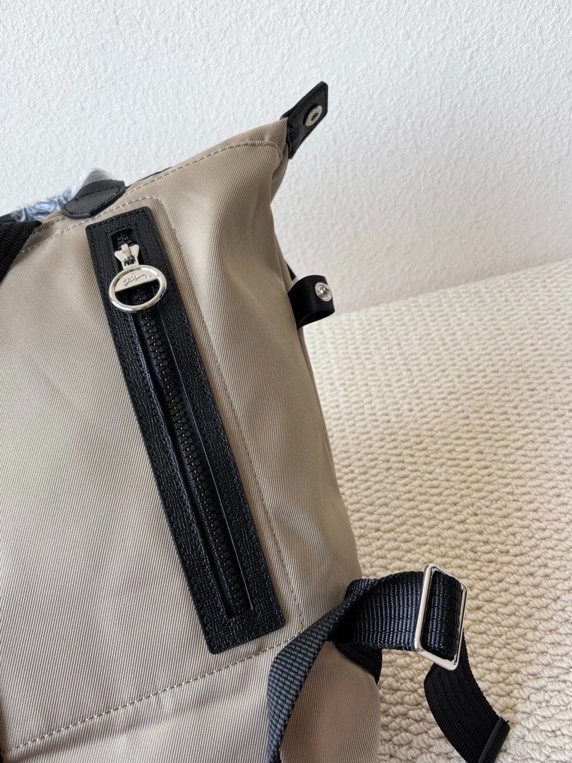 Longchamp Backpack (Category: Backpacks) located in Singapore. Submitted by sg_vela_professional_seller (Listing ID 1470204313, Image 4). Description: - Brand: Longchamp - Color: Neutral beige with black accents and hardware - Material: Lightweight, durable nylon fabric with sturdy straps - Features: Signature Longchamp branding, secure zippered outer pocket, and adjustable shoulder straps - Condition: Brand new and unused - Ideal for: Everyday c
