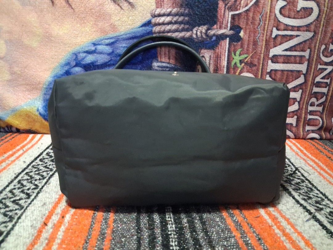 grey nylon tote bag (Category: Tote Bags) located in Angeles City. Submitted by anneps (Listing ID 1470214078, Image 3). Description: - Color: Grey - Material: Durable nylon with leather front flap and snap button fastener - Closure: Secure top zip closure - Interior: Spacious with a handy slip pocket and clean grey lining - Structure: Flat base keeps the bag standing upright - Handles: Comfortable top handles for easy carrying.