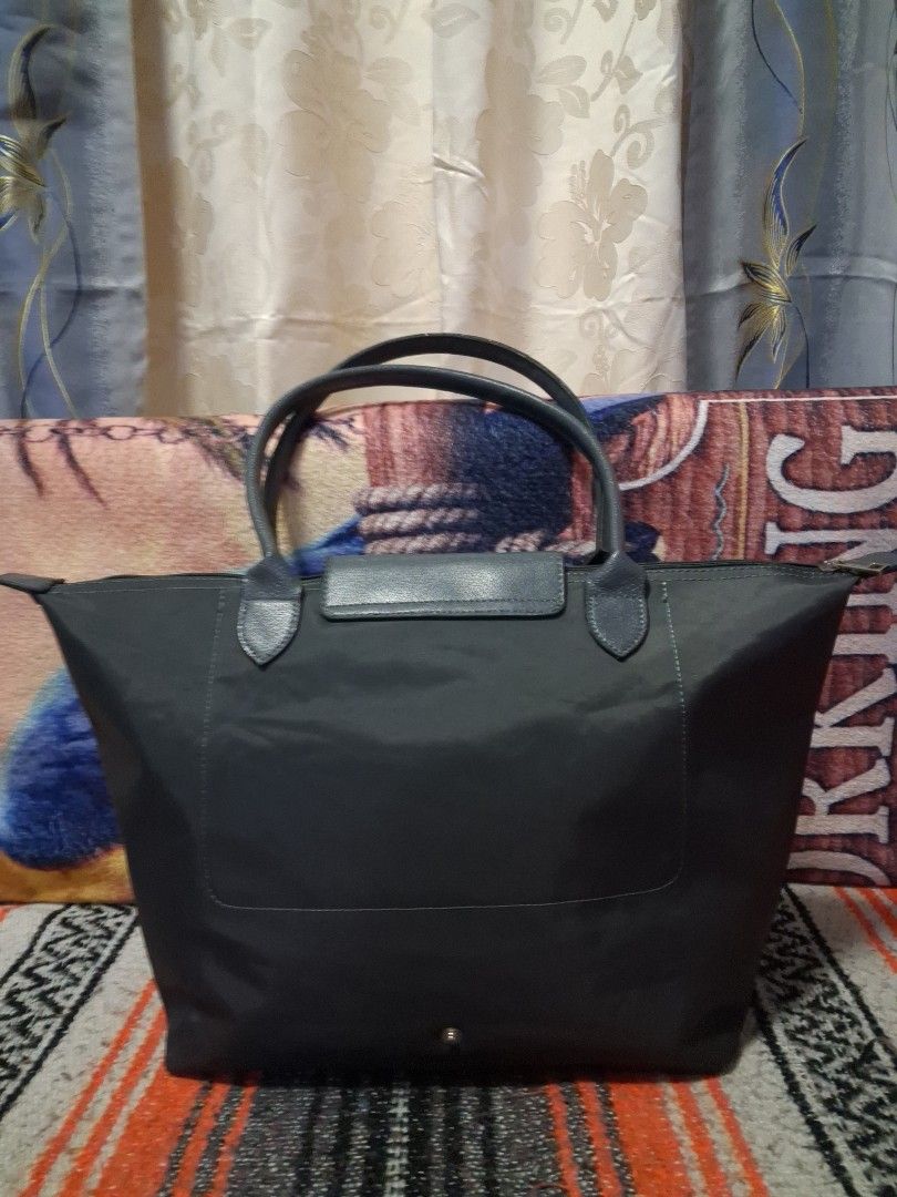 grey nylon tote bag (Category: Tote Bags) located in Angeles City. Submitted by anneps (Listing ID 1470214078, Image 2). Description: - Color: Grey - Material: Durable nylon with leather front flap and snap button fastener - Closure: Secure top zip closure - Interior: Spacious with a handy slip pocket and clean grey lining - Structure: Flat base keeps the bag standing upright - Handles: Comfortable top handles for easy carrying.