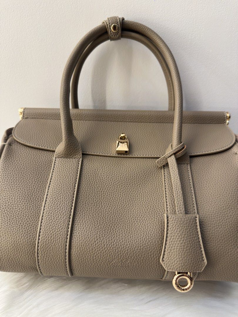 Loro Piana Tan Leather Handbag (Category: Luxury Bags & Wallets) located in Manila. Submitted by audreyhepburn21 (Listing ID 1470316882, Image 2). Description: - Authentic Loro Piana handbag crafted from luxury taupe pebbled leather - Made in Italy with immaculate stitching and structured top handles - Features a secure clasp strap and front flap design - Elegant gold padlock hardware accent with hanging charm ring - Versatile neutral earth tone 