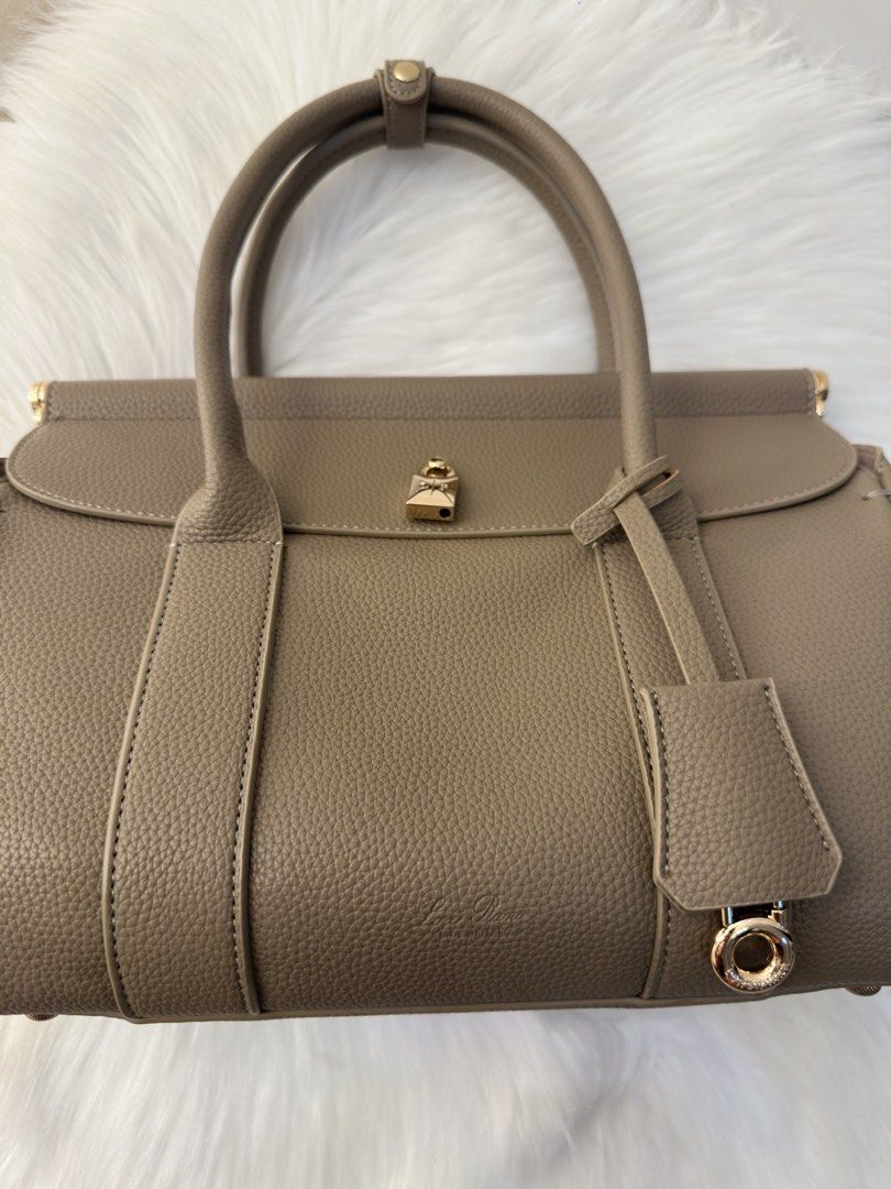 Loro Piana Tan Leather Handbag (Category: Luxury Bags & Wallets) located in Manila. Submitted by audreyhepburn21 (Listing ID 1470316882, Image 1). Description: - Authentic Loro Piana handbag crafted from luxury taupe pebbled leather - Made in Italy with immaculate stitching and structured top handles - Features a secure clasp strap and front flap design - Elegant gold padlock hardware accent with hanging charm ring - Versatile neutral earth tone 