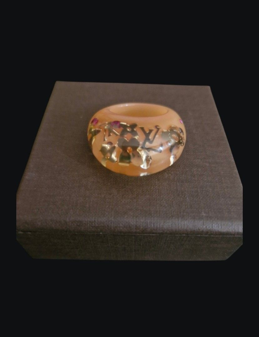Louis Vuitton Resin Monogram Ring with Box and Pouch (Category: Rings) located in Quezon City. Submitted by mglf1983 (Listing ID 1470174252, Image 3). Description: - Authentic Louis Vuitton resin ring in a gorgeous translucent peach orange shade - Features embedded gold monogram flowers, LV motifs, and delicate pink crystal accents - Trendy and bold chunky band design - Includes original brown cardboard box and velvet drawstring dust pouch - Perf