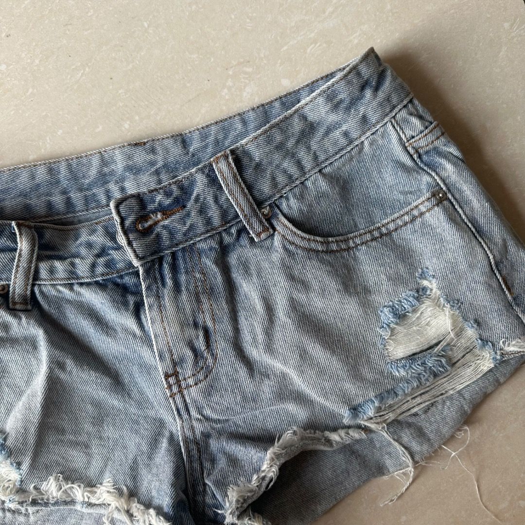 Low Waist Light Washed Denim Shorts (Category: Shorts) located in Paranaque City. Submitted by yanie.ae (Listing ID 1470166117, Image 2). Description: - Color/Wash: Light wash denim - Fit: Mid-rise with belt loops and front button closure - Style: Heavy distressing, rips on the right leg, and raw frayed hems - Pockets: Classic 5-pocket design - Material: Soft, comfortable cotton with a worn-in feel - Note: Measurements available upon request.