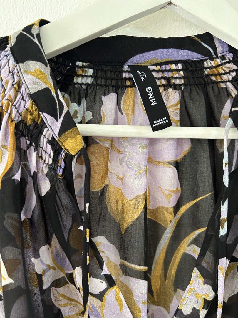 Mango Mango Black Floral Chiffon Blouse Size S (Category: Blouses) located in Manila. Submitted by isabelle_1104 (Listing ID 1470275732, Image 3). Description: - Brand: Mango - Design: Black with purple, lilac, and mustard yellow floral pattern - Neckline: V-neck with tie strings and shirring detail - Sleeves: Long balloon sleeves with smocked cuffs - Fabric: Sheer, lightweight material - Origin: Made in Morocco - Condition: Excellent pre-loved /