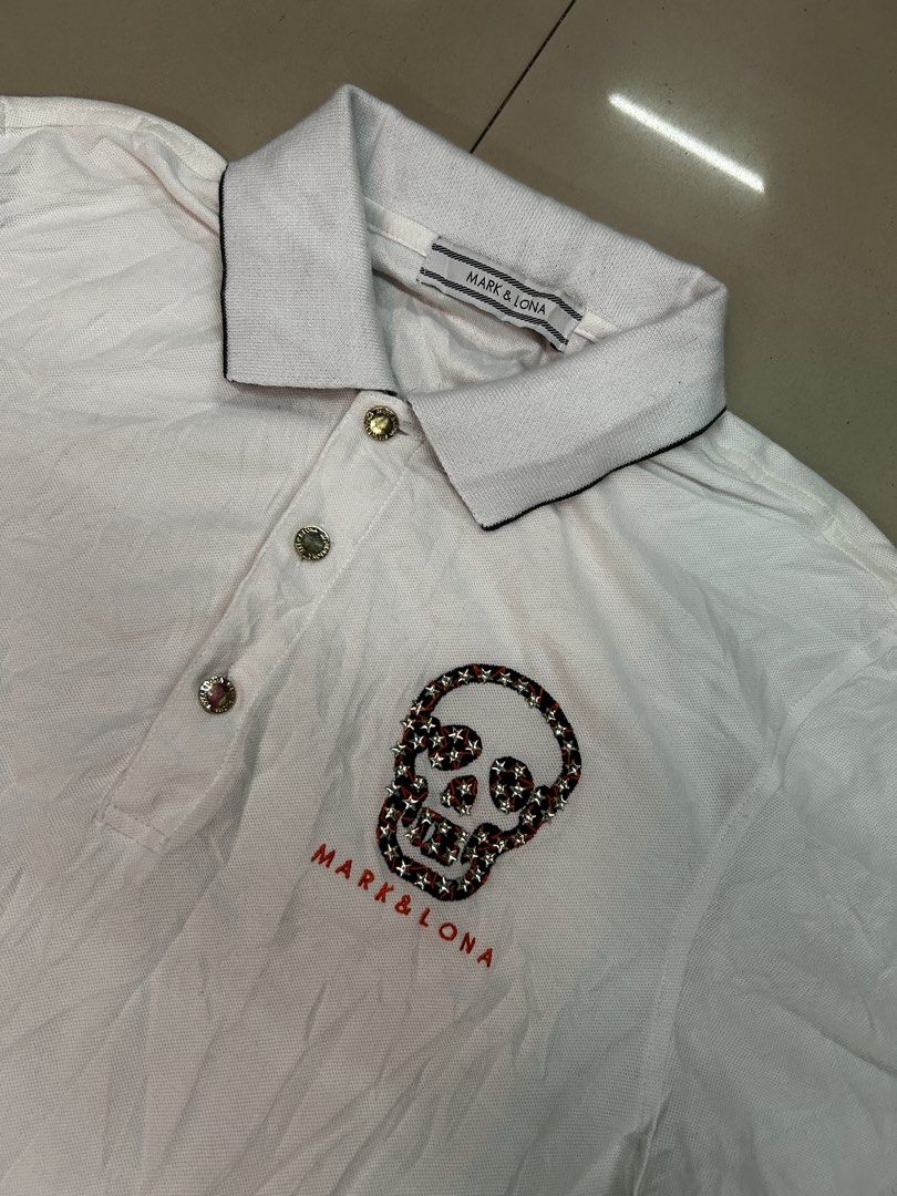 Mark & Lona White Skull Polo Shirt (Category: Tshirts & Polo Shirts ) located in Cebu City. Submitted by jkeive (Listing ID 1470197149, Image 2). Description: - Brand: Mark & Lona - Color: White - Size: Available upon request - Design: Short sleeves with black star pattern on cuffs, embroidered skull graphic and logo lettering on chest - Details: Classic collar with brand text on the back, gold buttons on placket, and embroidered golfer silhouett
