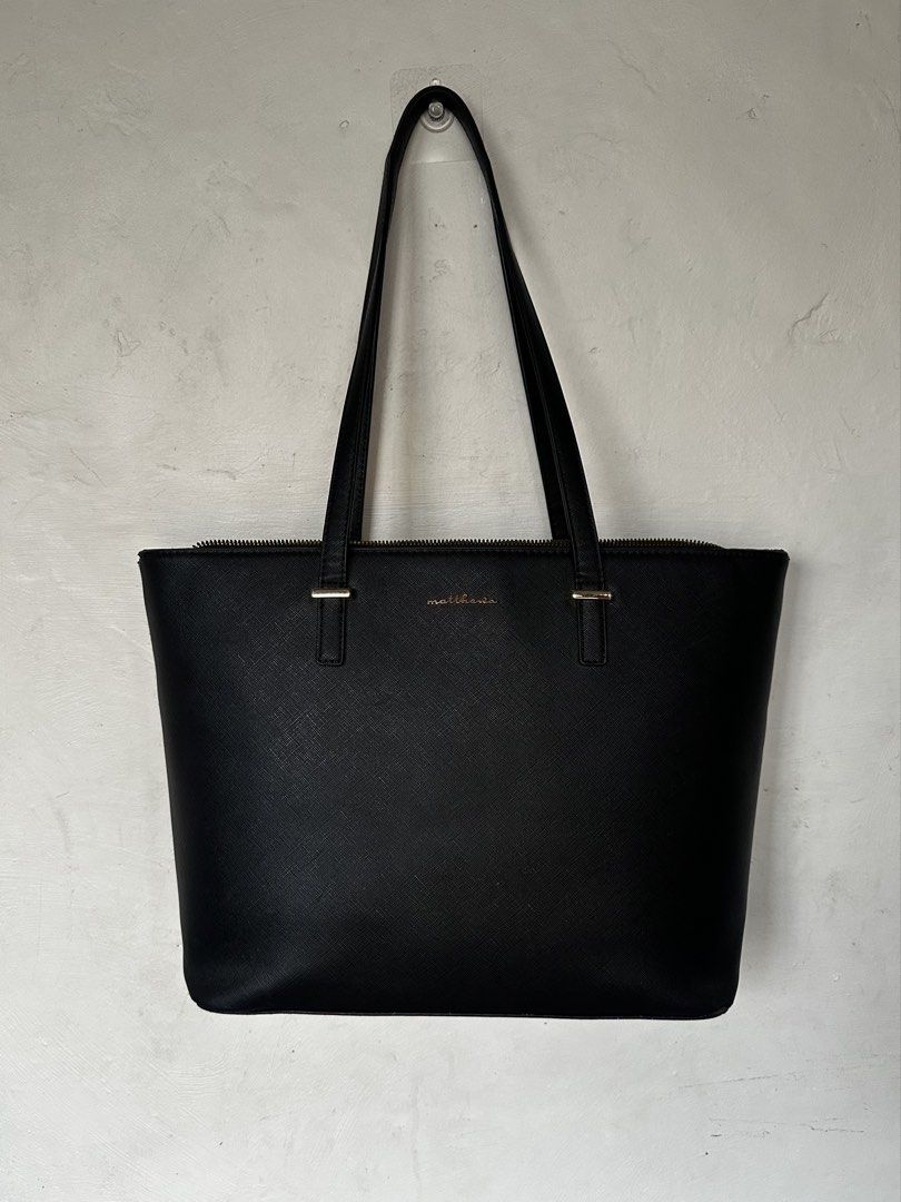 Matthews Black Leather Tote Bag (Category: Tote Bags) located in Manila. Submitted by omelette.12 (Listing ID 1470246821, Image 1). Description: - 1,799 original price, rfs: not using it anymore - Material: Premium Saffiano leather texture with chic gold lettering logo - Closure & Straps: Secure top zip closure with comfortable dual shoulder straps - Interior: Spacious compartment for all your daily essentials, laptop, or school items - Design: C