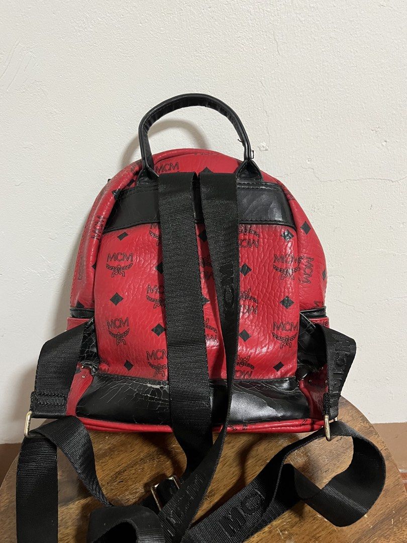 MCM Red Studded Leather Backpack (Category: Backpacks) located in Cabuyao City. Submitted by rdtrmt (Listing ID 1470151903, Image 2). Description: - Brand: MCM - Color: Bold red with black leather trim and silver-tone hardware - Design: Classic MCM monogram print covered in stylish metal studs - Features: Front zippered pocket with hardware pull, top grab handle, and signature front logo plaque - Straps: Adjustable black fabric shoulder straps fo