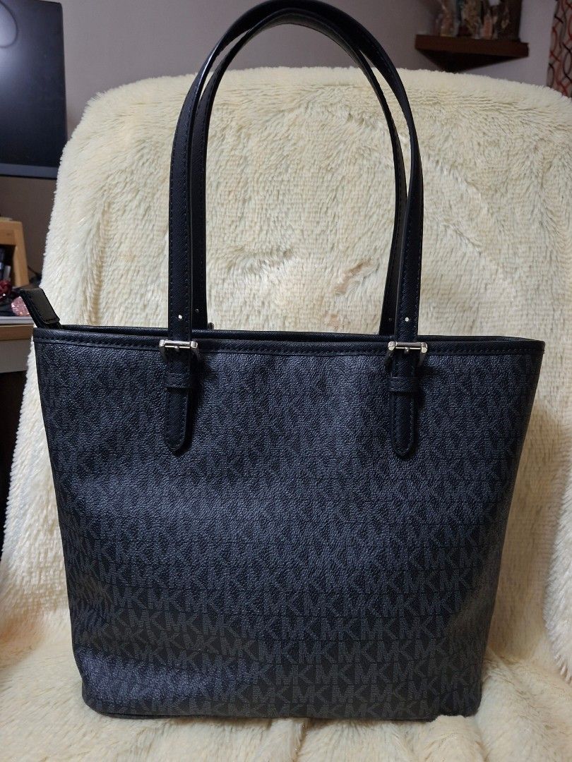 Michael Kors Black Monogram Tote Bag (Category: Tote Bags) located in Manila. Submitted by yanakolekzione (Listing ID 1470321959, Image 2). Description: - Pwede sa maselan super mukhang brand new Authentic black Michael Kors tote with all-over MK monogram pattern - Structured design featuring silver-tone hardware - Convenient front slip pocket with snap button closure - Secure main zip compartment with lined interior, zip pocket, and slip slots -
