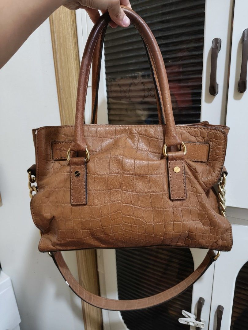 Michael Kors Brown Crocodile Embossed Leather Satchel (Category: Luxury Bags & Wallets) located in Manila. Submitted by luxph2 (Listing ID 1470219620, Image 2). Description: - Brand: Michael Kors - Material: Tan brown faux crocodile leather - Hardware: Gold-tone with protective bottom feet - Features: Dual top handles, adjustable crossbody strap, and front hanging lock charm - Interior: Zip pocket and clean fabric logo lining - Condition: Well ma