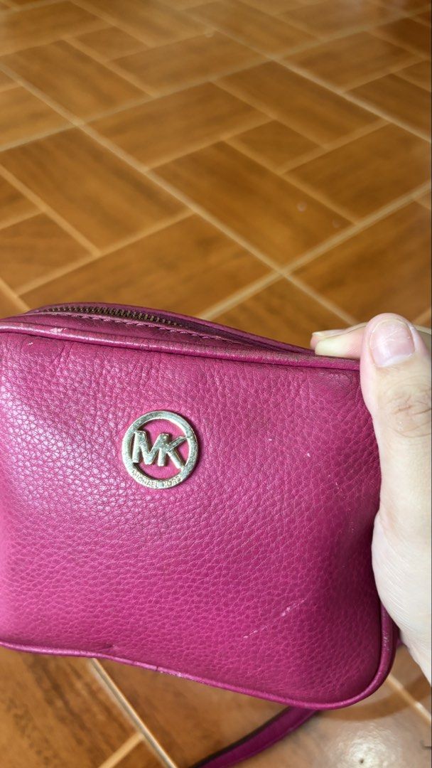 Michael Kors Pink Leather Crossbody Bag (Category: Cross-body Bags) located in Manila. Submitted by calliope777 (Listing ID 1470215599, Image 2). Description: - Brand: Michael Kors - Material: Bright pink pebbled leather - Hardware: Gold MK logo (shows minor wear) - Closure: Zip top - Interior: Signature fabric lining with 1 slip pocket and card slots - Strap: Adjustable leather crossbody strap - Condition: Minor wear on edges and hardware.