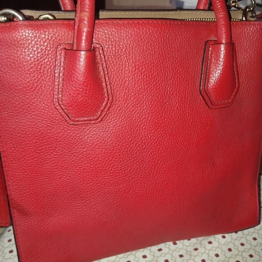 Michael Kors Red Leather Tote Bag (Category: Tote Bags) located in Manila. Submitted by lene48 (Listing ID 1470283405, Image 3). Description: Bright red pebbled leather tote bag from Michael Kors. Gold tone hardware and lettering logo on the front. Double top handles plus a detachable matching strap. Protective metal feet on the bottom base. Zip top closure. Clean inside lining. Great size for daily use, fits phones, keys, and a small wallet easi