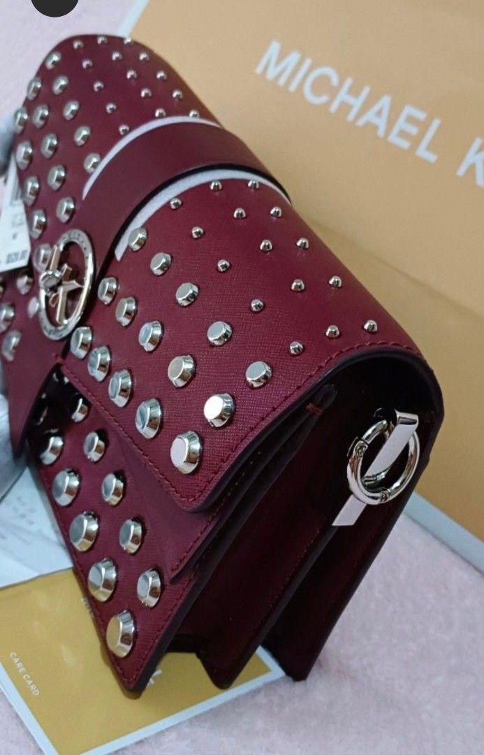 Michael Kors Studded Medium Convertible Leather Handbag Maroon (Category: Luxury Bags & Wallets) located in Quezon City. Submitted by shinereign (Listing ID 1470212995, Image 3). Description: - Authentic Michael Kors Saffiano leather bag in a rich maroon color - Edgy silver stud detailing with a chic circular MK logo snap closure - Versatile removable shoulder strap featuring a stylish chain-link accent - Organized interior with multiple compartm
