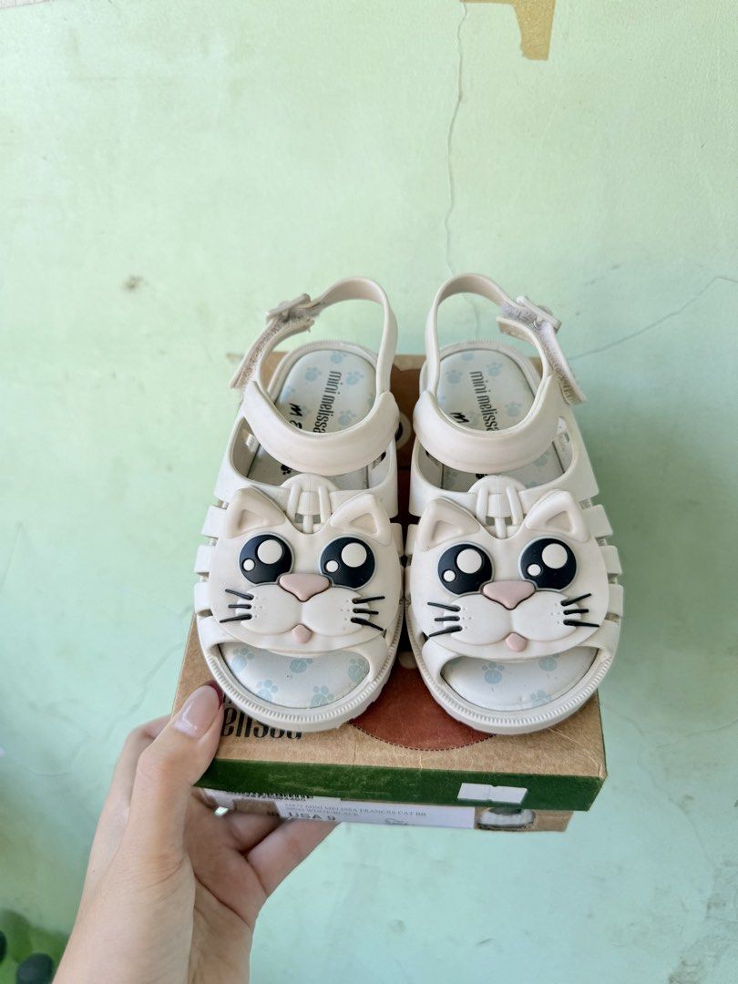 Mini Melissa Barbie and Cat Sandals Bundle (Category: Babies & Kids Fashion) located in Tuguegarao City. Submitted by declutteringmommaaa (Listing ID 1470168656, Image 2). Description: - Bundle of 2 pairs of genuine Mini Melissa kids shoes - Pair 1: Cream straps, layered bows, and adorable gold Barbie heart charms - Pair 2: Cute cartoon cat faces on the front with playful blue paw prints inside - Both pairs come with their original shoe boxes - D