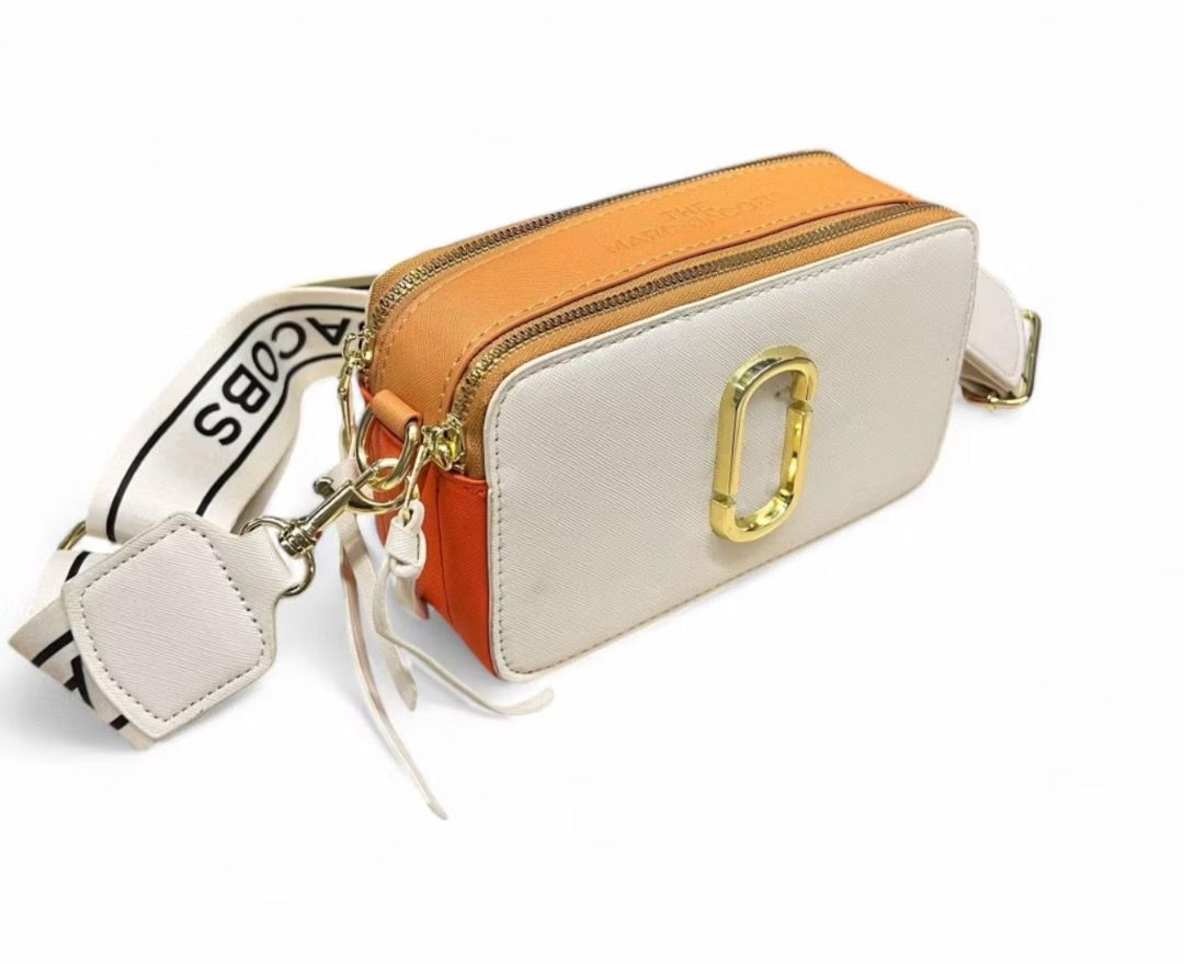 MJ The Snapshot Camera Bag (Category: Camera Bags & Carriers) located in Bulacan. Submitted by tytoluxe (Listing ID 1470206541, Image 2). Description: - Brand: MarcJacobs - Style: The Snapshot Camera Bag - Colorway: Striking Orange and White - Hardware: Gold-tone with iconic double J logo - Condition: Brand new (protective plastic still on front hardware) - Compartments: Double zip closure with top zip compartments - Strap: Includes fabric brande
