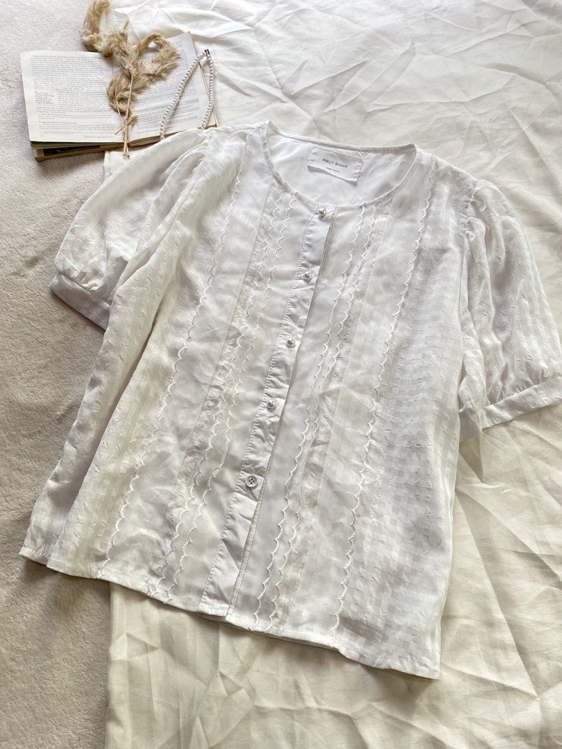 Molly Sugar White Short Sleeve Blouse Button Down Large 39 (Category: Blouses) located in Poro. Submitted by joyceyuu (Listing ID 1470167414, Image 2). Description: - Brand: Molly Sugar - Color: Classic White - Style: Short sleeve button-down blouse with round neckline - Features: Delicate lace trim panels and trendy puffed sleeves - Comfort: Fully lined interior fabric - Versatility: Perfect for both casual weekends and office outfits - Conditio