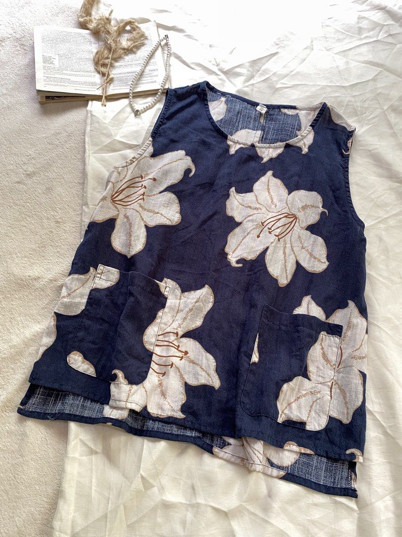 Navy Floral Sleeveless Top with Front Pockets Medium 37 (Category: Sleeveless) located in Poro. Submitted by joyceyuu (Listing ID 1470167591, Image 2). Description: - Color & Pattern: Navy blue with an all-over large white floral print - Design: Sleeveless, round neckline, and loose fit for ultimate comfort - Features: Two functional front pockets near the hem - Hemline: Trendy high-low cut with split sides - Fabric: Lightweight and breathable, i