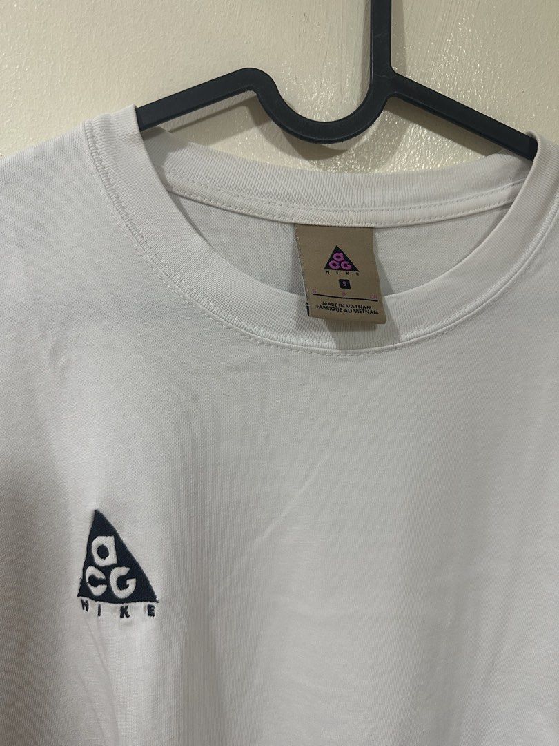 Nike ACG White T-Shirt (Category: Tshirts & Polo Shirts ) located in Manila. Submitted by rarewhale-91927a (Listing ID 1470215743, Image 2). Description: - Brand: Nike ACG - Color: White - Size: Small (Made in Vietnam) - Design: Small embroidered triangle logo on chest, crew neck, short sleeves - Fit: Standard fit cotton tee - Condition: Clean overall with minimal signs of wear.