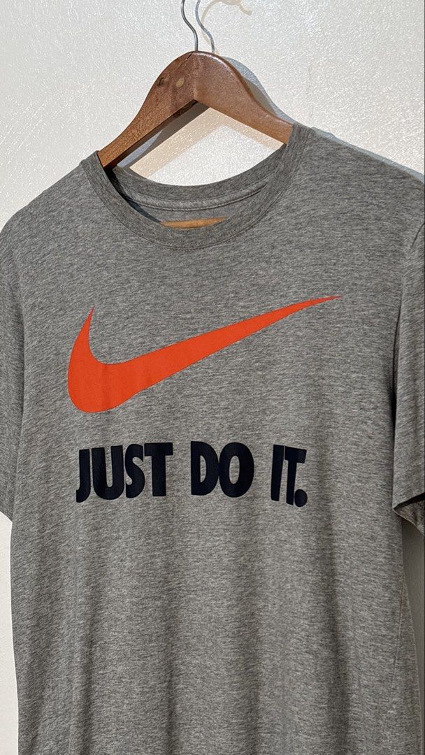 Nike Just Do It Grey T-shirt (Category: Tshirts & Polo Shirts ) located in Manila. Submitted by glano (Listing ID 1470299598, Image 2). Description: - Brand: Nike - Color: Grey with orange swoosh and black 'Just Do It' lettering - Size: Large (Regular fit) - Material: Soft and comfortable cotton blend - Details: Printed inner neck label with nikebetterworld.com - Ideal for: Everyday casual wear or workouts.