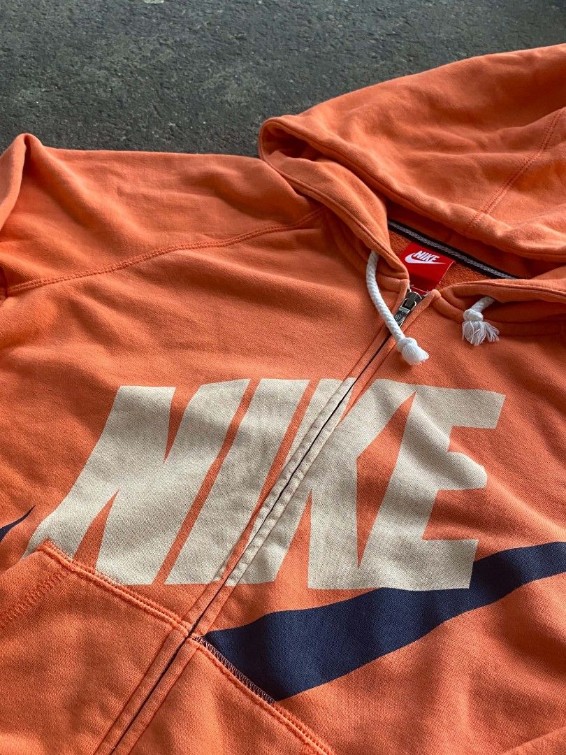 Nike Orange Zip-Up Hoodie (Category: Coats, Jackets and Outerwear) located in Manila. Submitted by raquimsyt (Listing ID 1470224771, Image 2). Description: - Brand: Nike - Style: Zip-up hoodie - Color: Bright orange with cream and navy front logo - Size: Medium (M) - Features: White drawstring hood with frayed tassel ends, front split kangaroo pocket, ribbed cuffs and hem - Condition: Pre-loved, well-maintained.