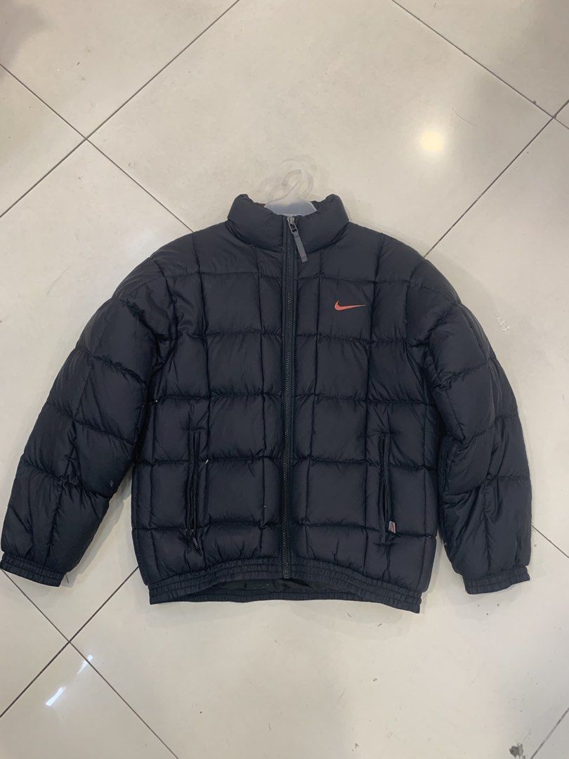 Nike Puffer Jacket Black with Orange Swoosh (Category: Coats, Jackets and Outerwear) located in Tarlac. Submitted by luxurious_apparel (Listing ID 1470265718, Image 1). Description: - Authentic Nike puffer jacket in classic black - Eye-catching bright orange embroidered swoosh logo on the chest - Stylish and warm quilted square stitching - Stand collar and full-zip front closure for extra protection - Two convenient zippered front pockets - Ribbe