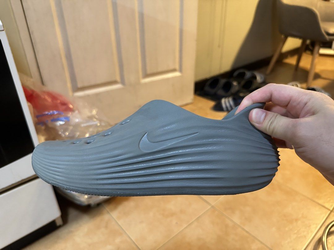 Nike Rejuven8 Smoke Grey US8 (Category: Slippers & Slides) located in Taguig. Submitted by marcomang17 (Listing ID 1470289199, Image 2). Description: - 9.5/10 - Used only dor a few months - Color: Smoke Grey - Style: Slip-on daily wear clogs - Material: Lightweight foam build with textured side grooves - Breathability: Multiple ventilation holes across the top - Branding: Silver Nike swoosh on the lateral side and Nike ReactX insole branding.