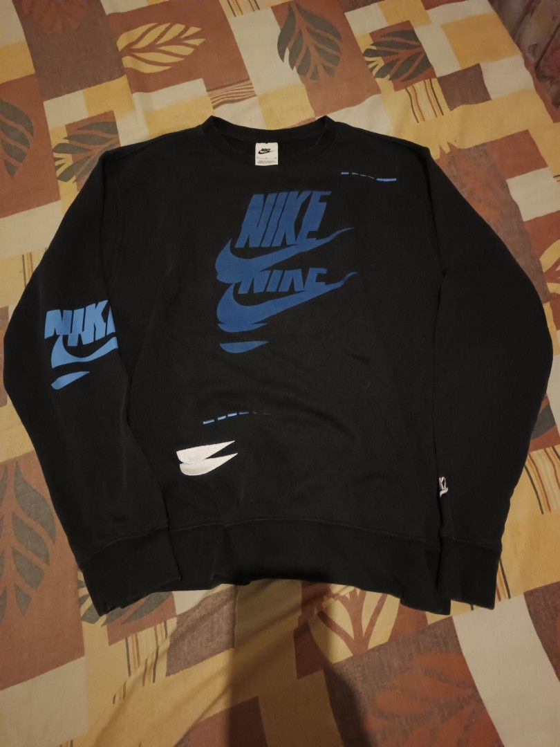 Nike sweet shirt (Category: Activewear) located in Odiongan. Submitted by thriftngo26 (Listing ID 1470267185, Image 1). Description: This item is the Nike Sportswear Sport Essentials+ Brushed Back Fleece Crew Sweatshirt (Style Code: DM6875-010 / DM6876-010), which features a "glitch in the system" graphic style with stacked, multi-colored Nike Futura logos scattered across the front and sleeves.