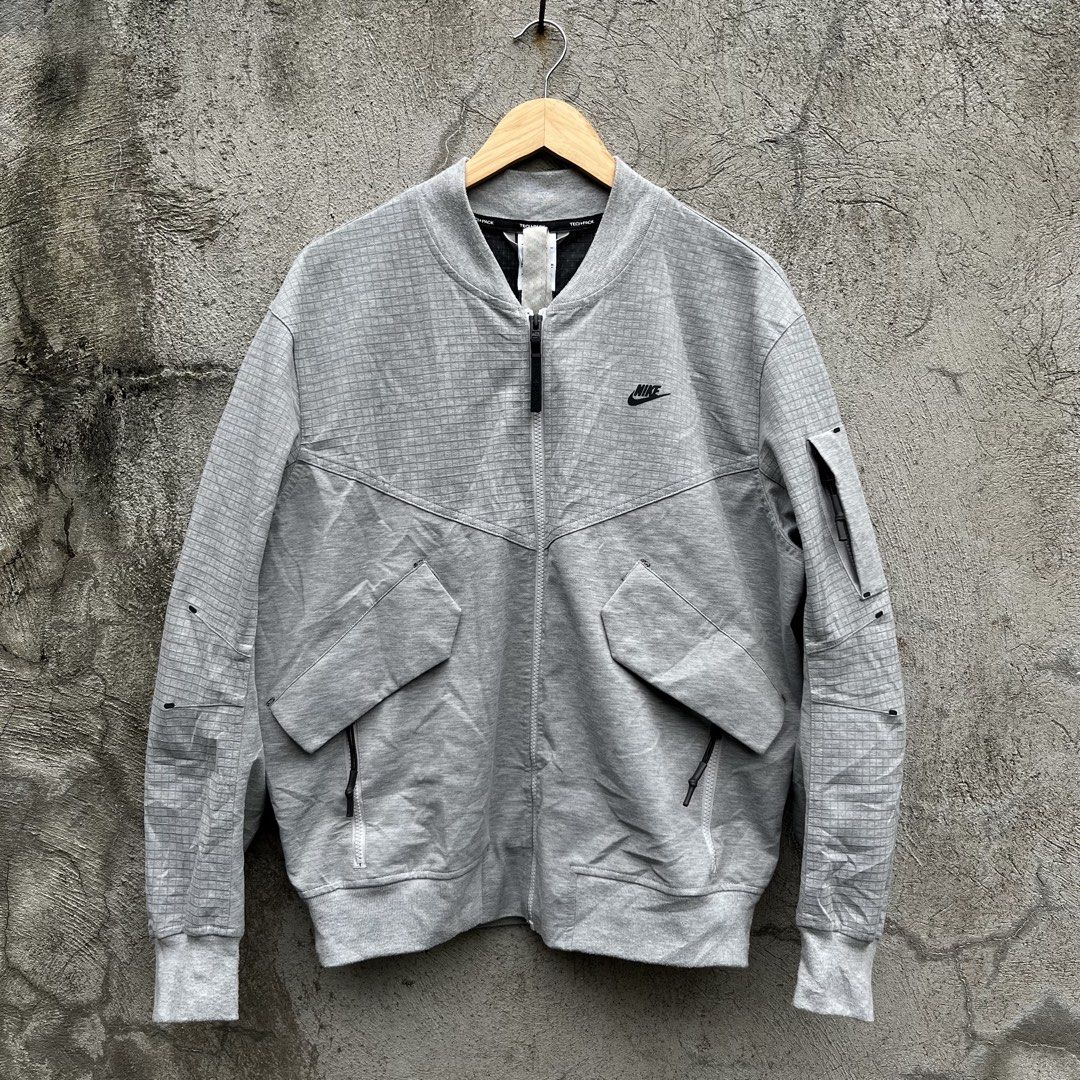 Nike Tech Pack Grid Bomber Jacket Grey (Category: Coats, Jackets and Outerwear) located in Davao. Submitted by streetsight (Listing ID 1470302444, Image 1). Description: - Brand: Nike Tech Pack - Style: Bomber jacket with full zip closure - Color: Light grey with all-over grid pattern - Details: Black Nike logo embroidery, angled front pockets, left sleeve utility pocket, interior collar straps - Finish: Ribbed cuffs and hem - Size: Medium - Orig