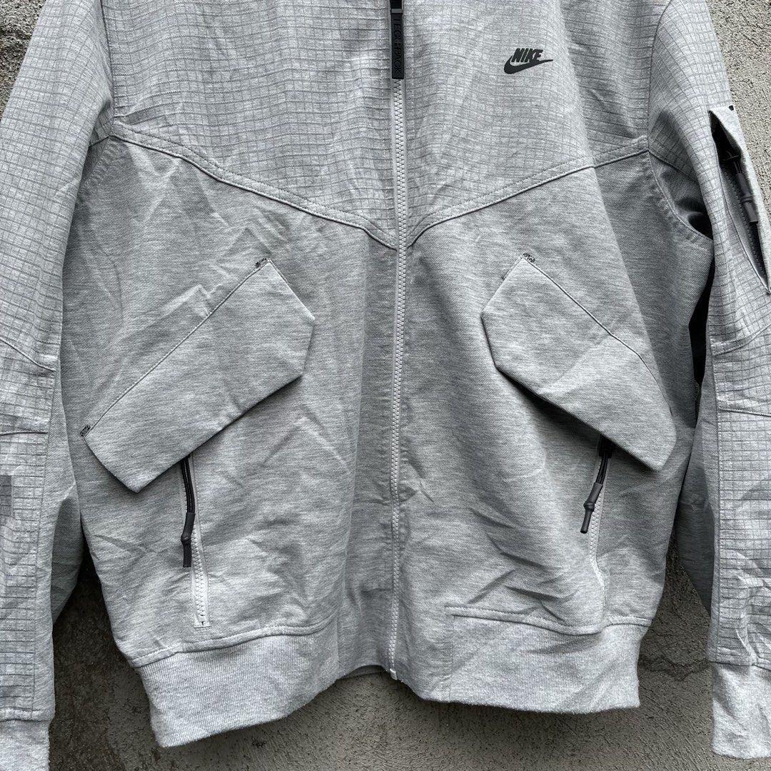 Nike Tech Pack Grid Bomber Jacket Grey (Category: Coats, Jackets and Outerwear) located in Davao. Submitted by streetsight (Listing ID 1470302444, Image 3). Description: - Brand: Nike Tech Pack - Style: Bomber jacket with full zip closure - Color: Light grey with all-over grid pattern - Details: Black Nike logo embroidery, angled front pockets, left sleeve utility pocket, interior collar straps - Finish: Ribbed cuffs and hem - Size: Medium - Orig