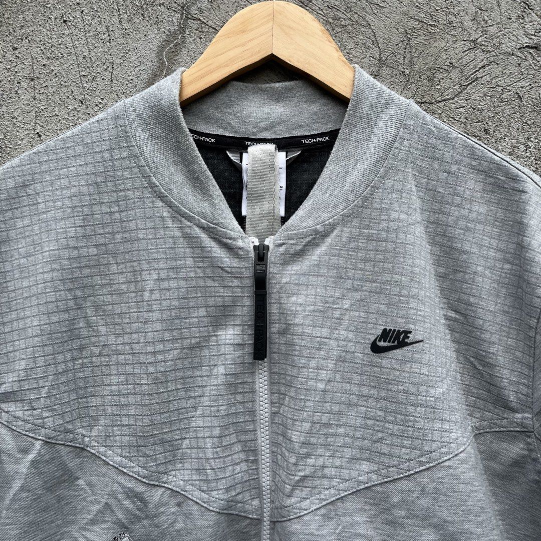 Nike Tech Pack Grid Bomber Jacket Grey (Category: Coats, Jackets and Outerwear) located in Davao. Submitted by streetsight (Listing ID 1470302444, Image 2). Description: - Brand: Nike Tech Pack - Style: Bomber jacket with full zip closure - Color: Light grey with all-over grid pattern - Details: Black Nike logo embroidery, angled front pockets, left sleeve utility pocket, interior collar straps - Finish: Ribbed cuffs and hem - Size: Medium - Orig