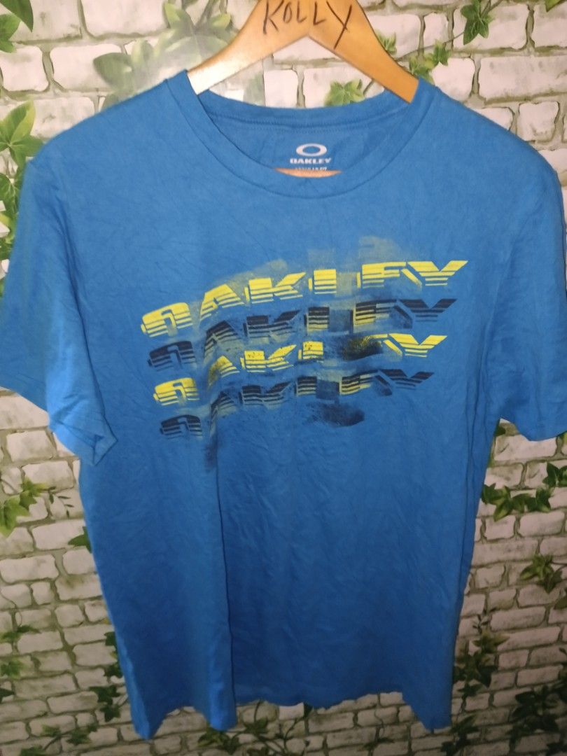 Oakley Blue Graphic Tee Size M (Category: Tshirts & Polo Shirts ) located in Carcar. Submitted by rolandobac92675 (Listing ID 1470268526, Image 2). Description: - Brand: Oakley - Color: Bright blue with a multi-layer yellow and blue graphic logo - Size: Medium - Fit: Regular fit with a comfortable crew neck - Origin: Made in Honduras - Condition: Clean fabric, short sleeves, ready to wear.