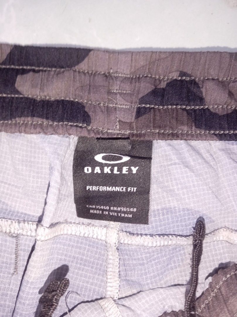 Oakley Performance Fit Camouflage Shorts (Category: Shorts) located in Nagcarlan. Submitted by asd0606 (Listing ID 1470240882, Image 3). Description: - Authentic Oakley performance shorts in a brown/black camouflage pattern - Comfortable performance fit with an elastic waistband and adjustable drawstring - Lightweight grid fabric construction inside for enhanced breathability - Features a small Oakley ellipse logo printed on the lower left leg - 