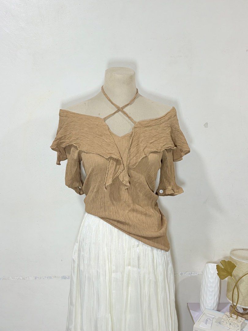 Off-shoulder ruffle top in light brown size medium to large (Category: Blouses) located in Manila. Submitted by biacakes (Listing ID 1470262774, Image 2). Description: - Color: Light brown - Style: Off-shoulder blouse with short sleeves - Design: Ruffled neckline and criss-cross halter straps - Fit: Relaxed fit, hits past the waistline - Material: Soft textured fabric - Size: Fits Medium to Large - Condition: Great addition to your casual wardrob