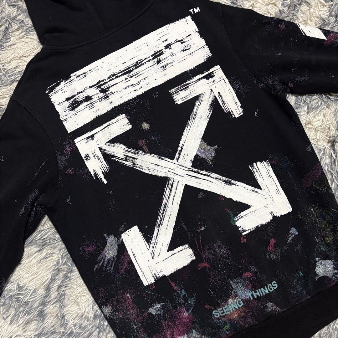Off-White Paint Splatter Zip-Up Hoodie (Category: Coats, Jackets and Outerwear) located in Caloocan City. Submitted by jerichotad22965 (Listing ID 1470196944, Image 2). Description: - Brand: Off-White - Color: Black with paint splatter effect throughout - Design: Signature sleeve diagonals, large back brush arrow graphic, and 'SEEING THINGS' lettering - Details: Green 'MAIN LABEL' collar tag with 2019 copyright, diagonal stripe wash tag, and ring