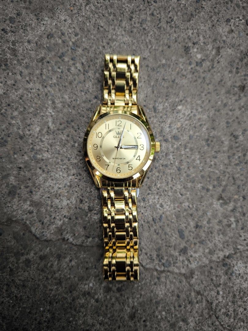 Olevs Gold Quartz Analog Watch (Category: Women's Watches) located in Nabua. Submitted by thrift2currency (Listing ID 1470237910, Image 1). Description: - Brand: Olevs - Style: Elegant gold-tone quartz watch with polished metal links - Dial: Shiny gold finish with clear number markers and 3 o'clock date window - Closure: Secure butterfly clasp with engraved brand logo - Durability: Stainless steel back case and 3 ATM water resistance - Performanc