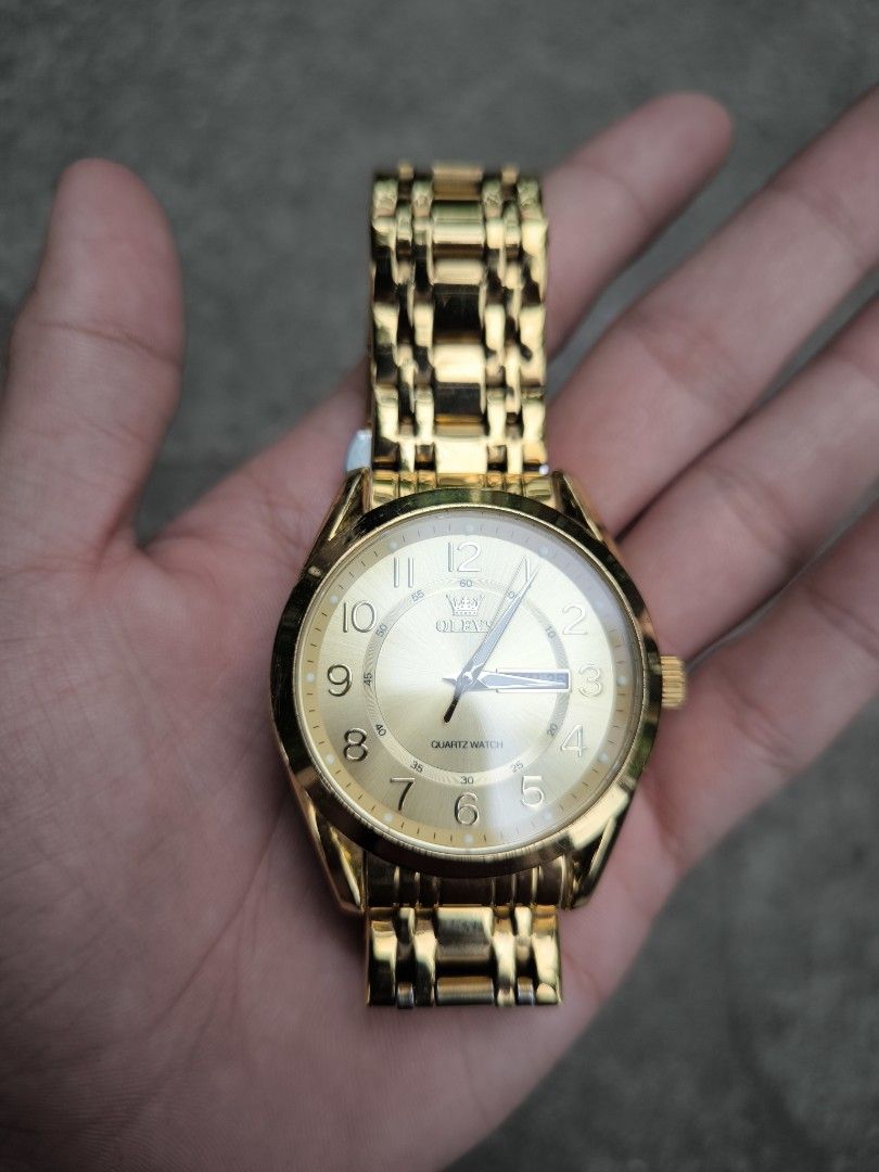 Olevs Gold Quartz Analog Watch (Category: Women's Watches) located in Nabua. Submitted by thrift2currency (Listing ID 1470237910, Image 3). Description: - Brand: Olevs - Style: Elegant gold-tone quartz watch with polished metal links - Dial: Shiny gold finish with clear number markers and 3 o'clock date window - Closure: Secure butterfly clasp with engraved brand logo - Durability: Stainless steel back case and 3 ATM water resistance - Performanc