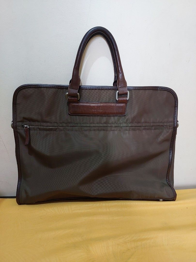 Paul Smith Brown Nylon Leather Briefcase Bag (Category: Briefcases) located in Malabon City. Submitted by jullie_bag_shop (Listing ID 1470271031, Image 1). Description: - Authentic Paul Smith briefcase in stylish brown nylon and leather - Double top handles with embossed logo patch - Secure zip exterior closure with magnetic snap top - Spacious interior lined in brown fabric with signature red trim - Includes internal zipped pocket, slip pockets,